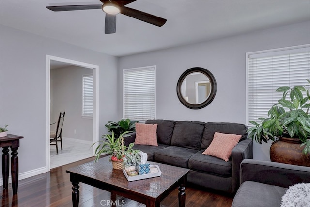 living area featuring a ceiling fan, dark wood-type flooring, and baseboards