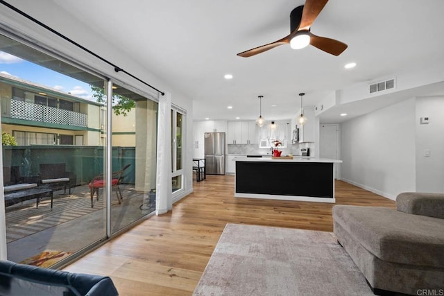 living room with light wood finished floors, recessed lighting, a ceiling fan, and baseboards
