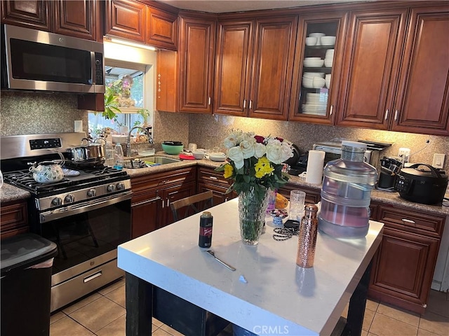 702 N Burris Ave, Compton, CA 90221 - kitchen featuring stainless steel appliances, a sink, light tile patterned floors, and backsplash