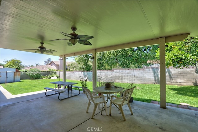 view of patio / terrace featuring outdoor dining area, a storage shed, a ceiling fan, and an outbuilding