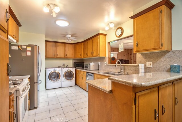 kitchen featuring appliances with stainless steel finishes, independent washer and dryer, a sink, light tile patterned floors, and brown cabinetry