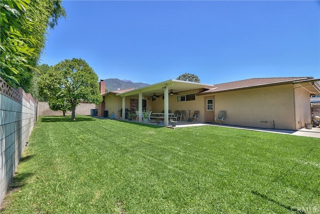 rear view of property with ceiling fan, stucco siding, a patio, and a chimney