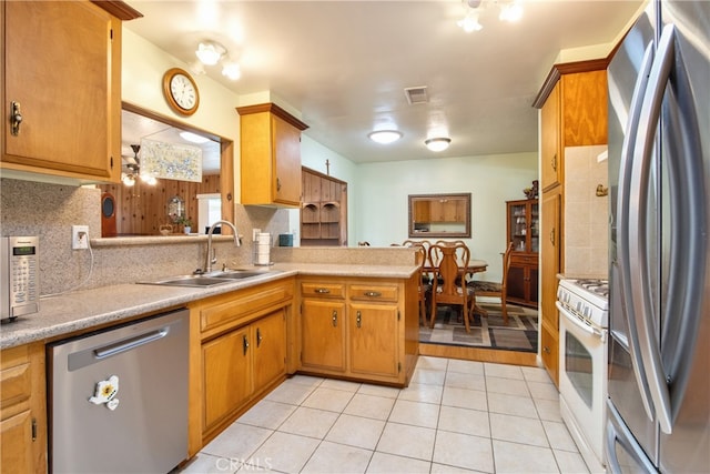 kitchen featuring stainless steel appliances, a sink, decorative backsplash, and light countertops