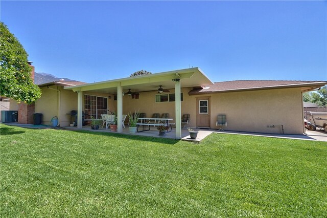 back of property with stucco siding, ceiling fan, a patio, a lawn, and central AC