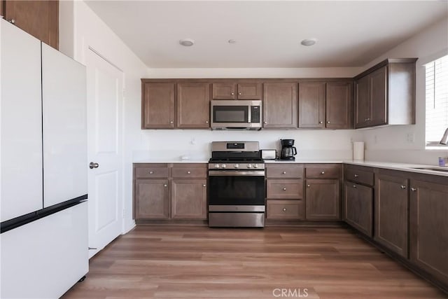 959 Rockcress Ln, Banning, CA 92220 - kitchen featuring stainless steel appliances, light countertops, a sink, light wood-style floors, and dark brown cabinets