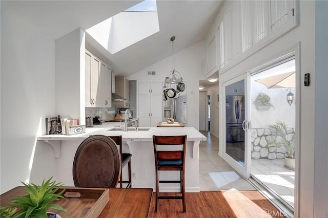 25552 Paseo La Vis Unit 20, Laguna Niguel, CA 92677 - kitchen with a sink, a peninsula, light countertops, a kitchen breakfast bar, and pendant lighting