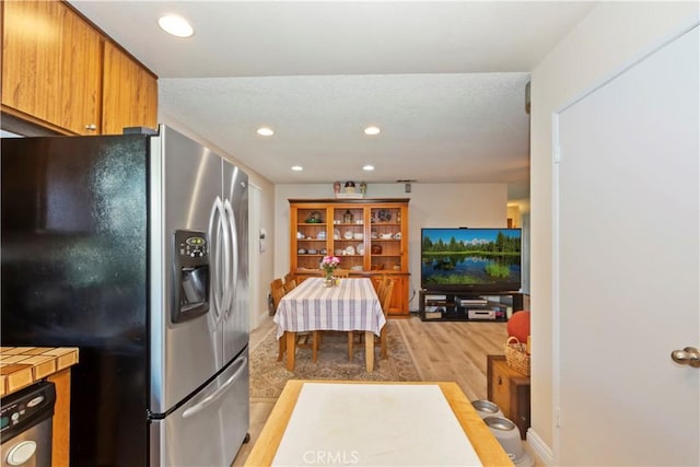 7030 Idyllwild Ln, Riverside, CA 92503 - kitchen with stainless steel refrigerator with ice dispenser, light wood-style floors, recessed lighting, brown cabinetry, and tile countertops