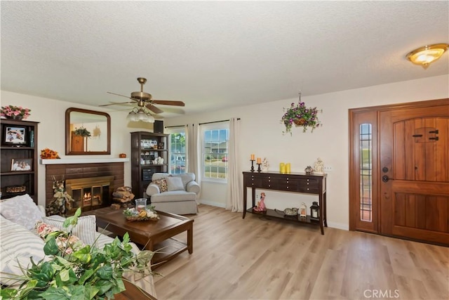 7030 Idyllwild Ln, Riverside, CA 92503 - living area with a textured ceiling, light wood-style floors, ceiling fan, a fireplace, and baseboards