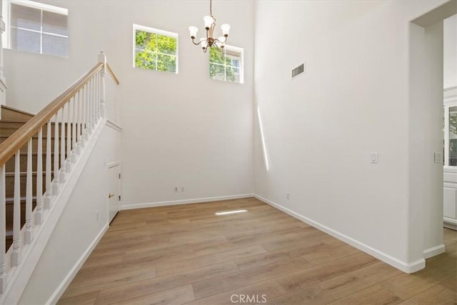 2923 Cottage Ln, Paso Robles, CA 93446 - unfurnished dining area with light wood-style floors, a towering ceiling, a chandelier, baseboards, and stairs
