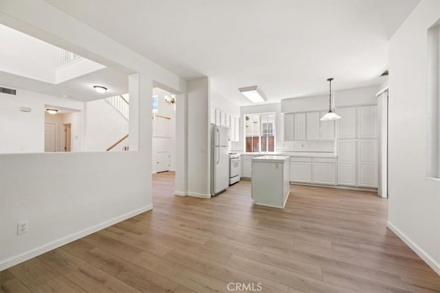 2923 Cottage Ln, Paso Robles, CA 93446 - kitchen with white appliances, a kitchen island, white cabinets, light wood finished floors, and baseboards