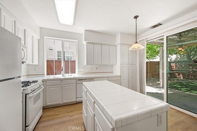 2923 Cottage Ln, Paso Robles, CA 93446 - kitchen with white appliances, tile counters, light wood-style floors, and a sink