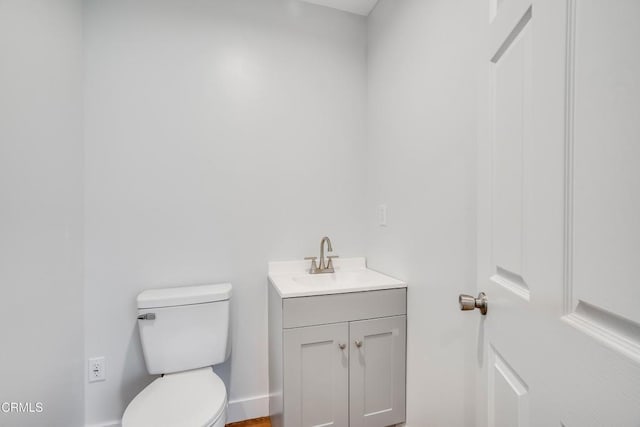bathroom featuring toilet, vanity, and baseboards