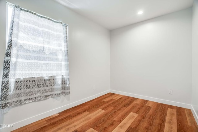 spare room featuring wood finished floors, baseboards, and recessed lighting