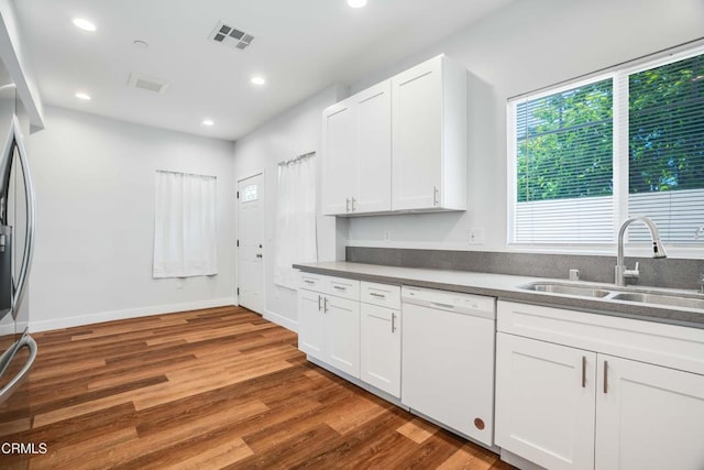 kitchen featuring dishwasher, a sink, wood finished floors, white cabinets, and recessed lighting