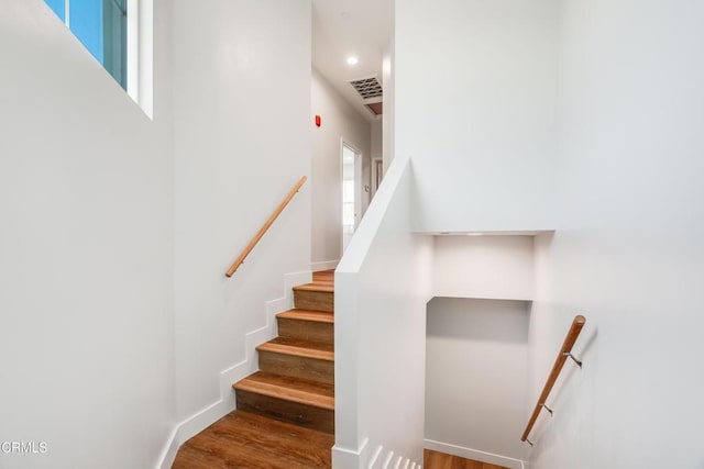 stairs with wood finished floors, recessed lighting, and baseboards