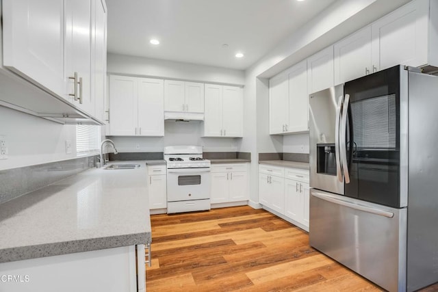 kitchen with stainless steel fridge with ice dispenser, white range with gas cooktop, a sink, light wood-style floors, and white cabinets