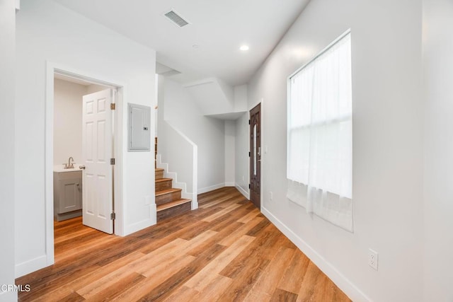 unfurnished room featuring light wood finished floors, stairs, baseboards, a sink, and recessed lighting