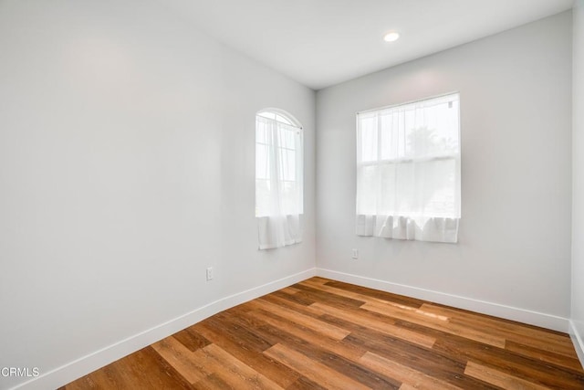 empty room featuring baseboards, wood finished floors, and recessed lighting