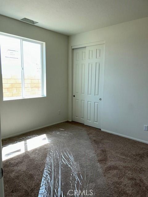 unfurnished bedroom with a closet, carpet, and baseboards