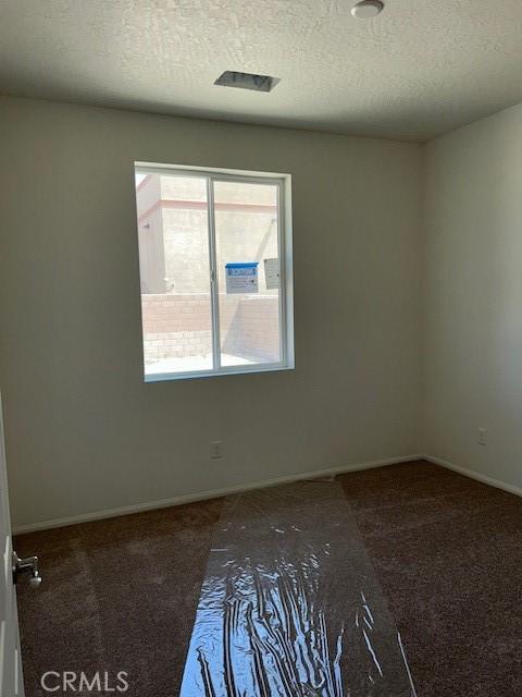 carpeted empty room with baseboards and a textured ceiling