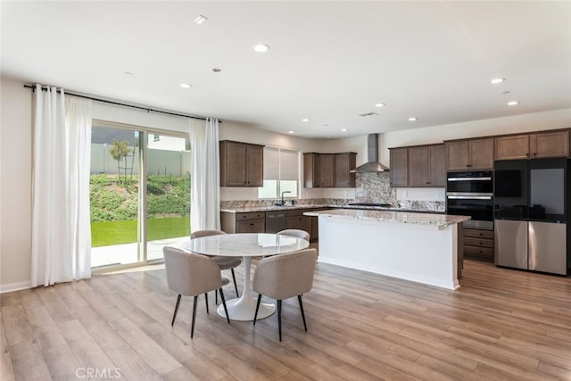 25367 Circle Stone Dr, Menifee, CA 92586 - kitchen with stainless steel appliances, wall chimney range hood, light wood-style floors, recessed lighting, and dark brown cabinetry