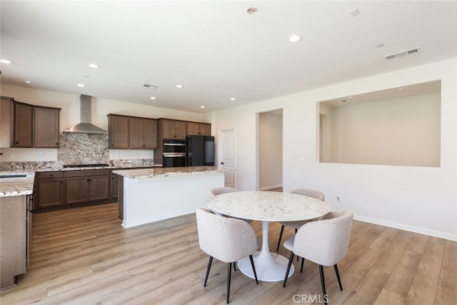 25367 Circle Stone Dr, Menifee, CA 92586 - kitchen with wall chimney range hood, a kitchen island, gas stovetop, recessed lighting, and freestanding refrigerator