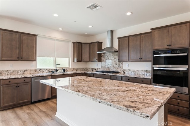 25367 Circle Stone Dr, Menifee, CA 92586 - kitchen featuring stainless steel appliances, wall chimney exhaust hood, a sink, a kitchen island, and dark brown cabinetry