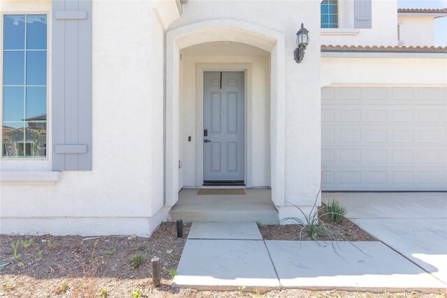 25367 Circle Stone Dr, Menifee, CA 92586 - doorway to property featuring stucco siding, driveway, and an attached garage