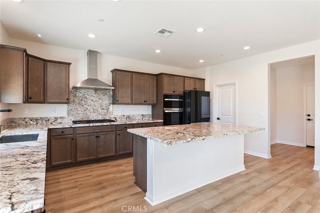 25367 Circle Stone Dr, Menifee, CA 92586 - kitchen featuring wall chimney range hood, black appliances, a sink, a center island, and light wood-style floors