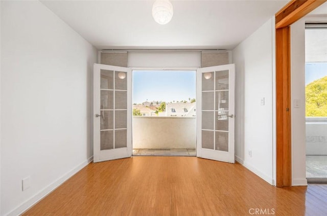 spare room featuring wood finished floors, french doors, and baseboards