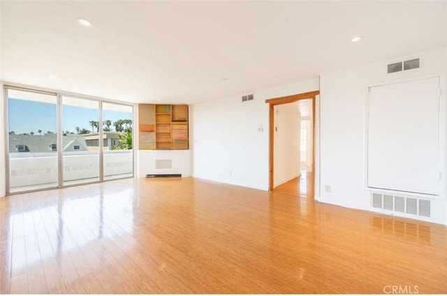 unfurnished room with wood finished floors, recessed lighting, and floor to ceiling windows