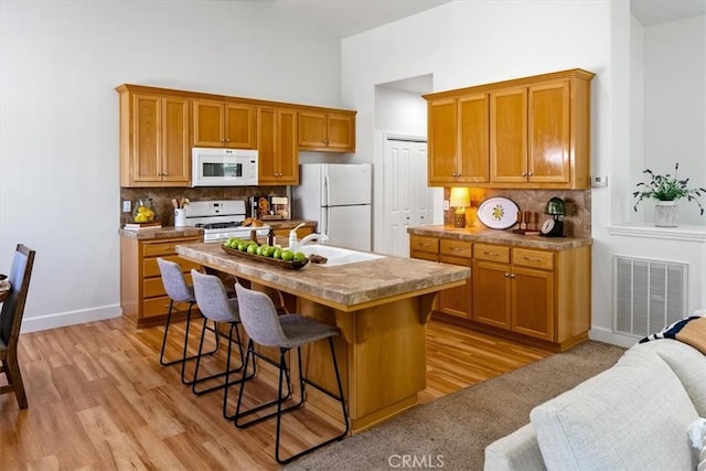 511 3rd St, Paso Robles, CA 93446 - kitchen featuring white appliances, a kitchen bar, tasteful backsplash, brown cabinetry, and a high ceiling