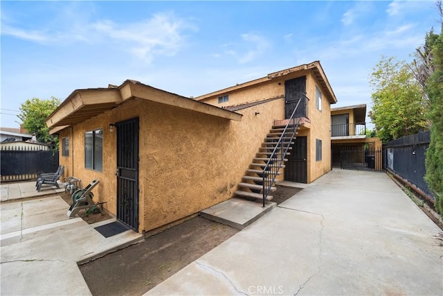 view of home's exterior featuring stairs, fence, and stucco siding