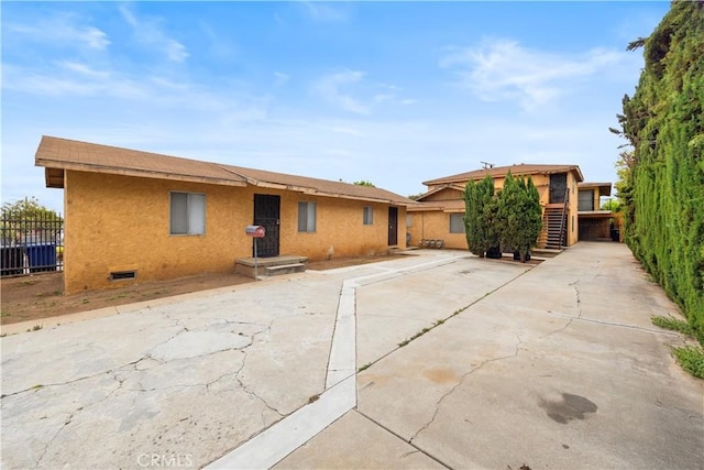 view of front facade featuring stucco siding and fence