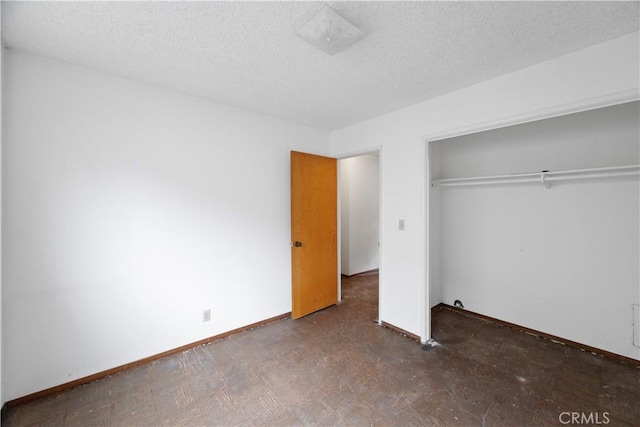 unfurnished bedroom with baseboards, a textured ceiling, and a closet