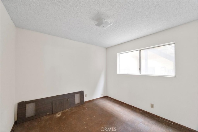 unfurnished room with a textured ceiling, tile patterned floors, and baseboards