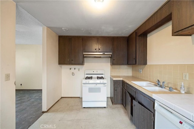 kitchen featuring white appliances, a sink, tile countertops, under cabinet range hood, and decorative backsplash