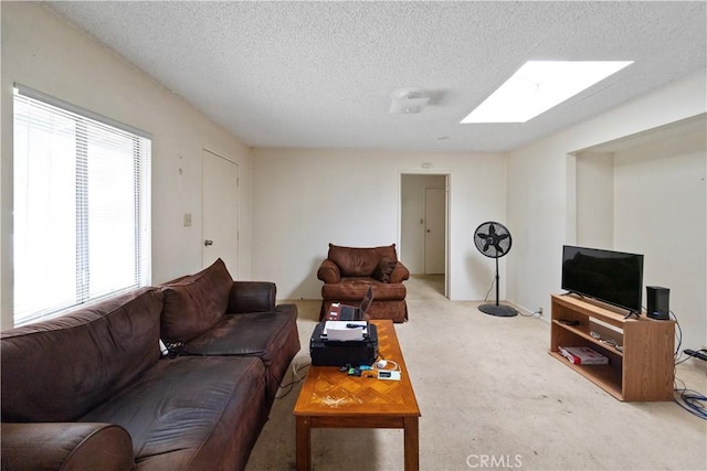 living room featuring a textured ceiling, carpet floors, and a skylight