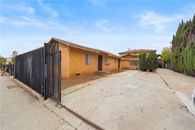 rear view of property featuring fence, stucco siding, and crawl space