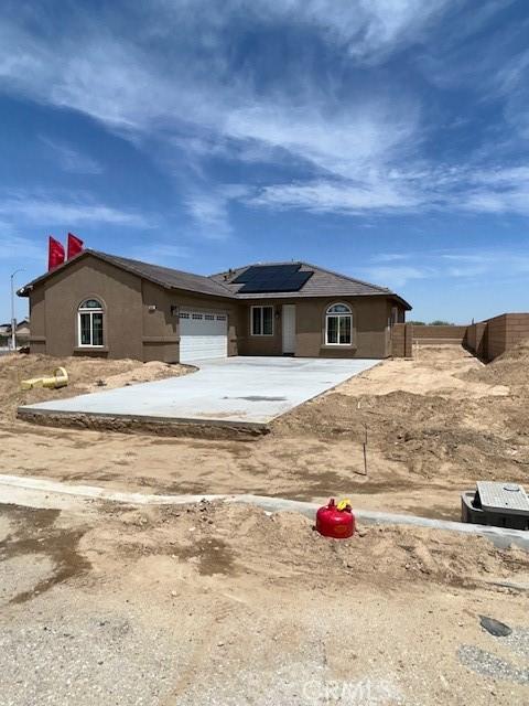 view of front of property with solar panels, driveway, a garage, and stucco siding