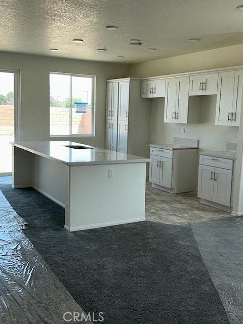 kitchen with a center island, white cabinets, baseboards, and a textured ceiling