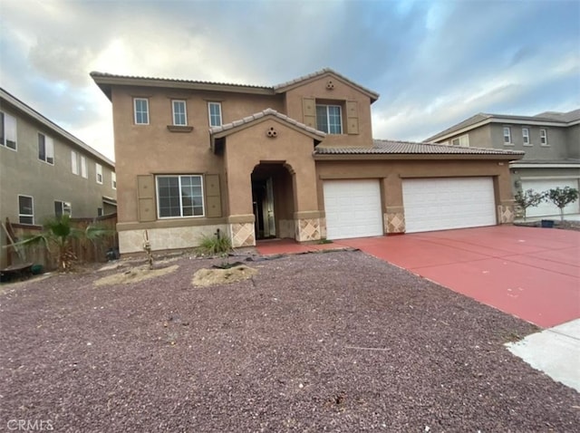 mediterranean / spanish house with stucco siding, concrete driveway, a tile roof, and a garage