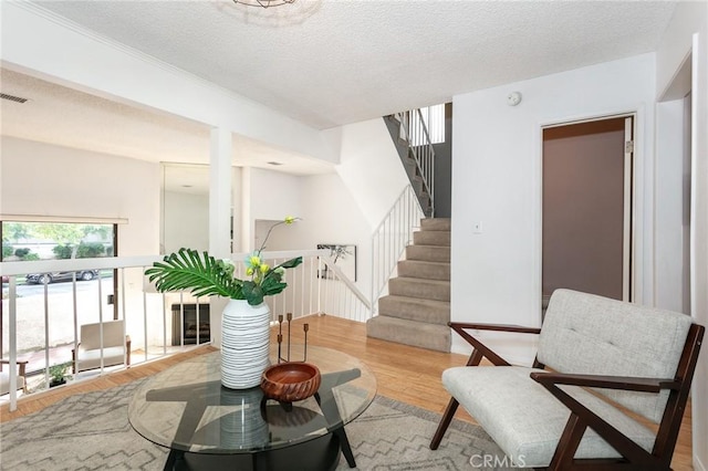 living area featuring wood finished floors, a textured ceiling, and stairs