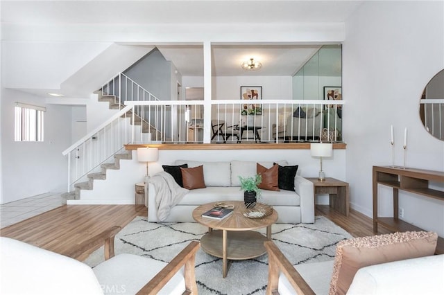 living room featuring wood finished floors, stairs, and baseboards