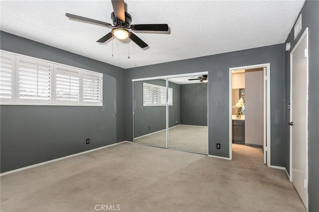 unfurnished bedroom featuring carpet flooring, a closet, a textured ceiling, a ceiling fan, and baseboards