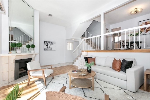 living room featuring stairway, wood finished floors, and a tiled fireplace