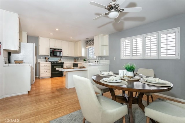 dining room with light wood-type flooring, ceiling fan, recessed lighting, and baseboards