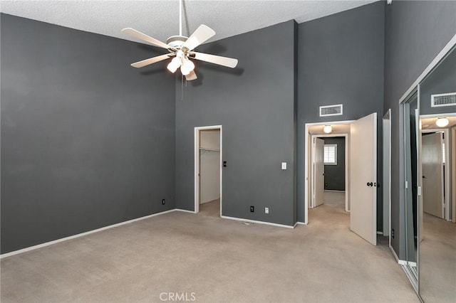 unfurnished bedroom with a towering ceiling, light colored carpet, baseboards, a closet, and ceiling fan