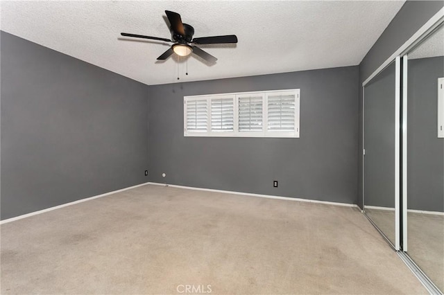 unfurnished bedroom with carpet flooring, a closet, baseboards, and a textured ceiling