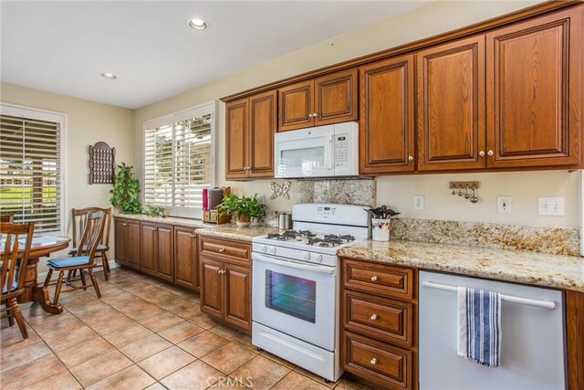 684 Big Spring Dr, Banning, CA 92220 - kitchen with white appliances, brown cabinets, light tile patterned flooring, recessed lighting, and light stone countertops